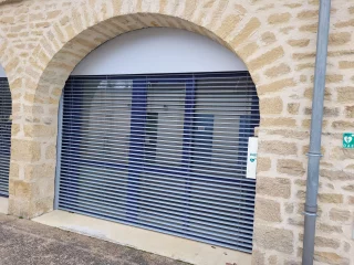 Brise-soleil à lames grises dans une ouverture cintrée à Buxy