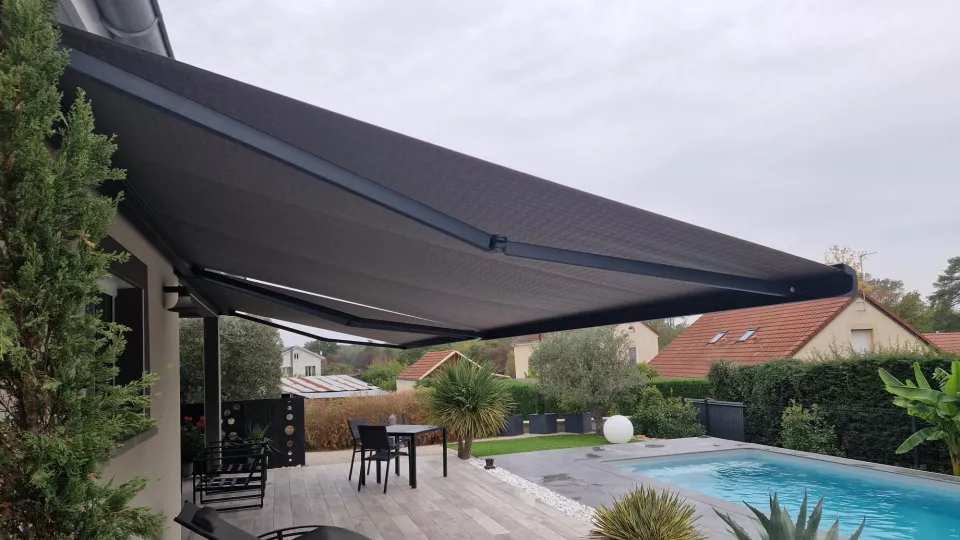 Store banne gris déployé au-dessus d’une terrasse près d’une piscine à La Charmée