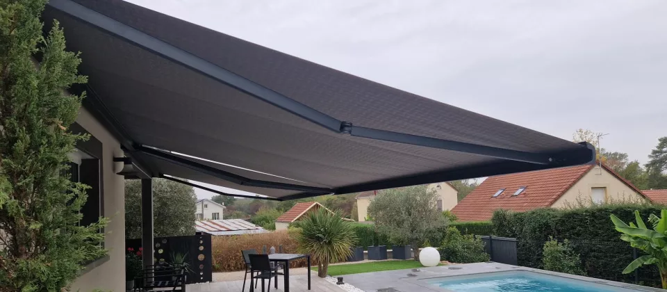 Store banne gris déployé au-dessus d’une terrasse près d’une piscine à La Charmée