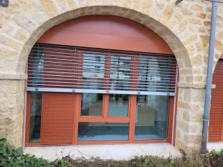 Brise-soleil orange devant une baie cintrée à Buxy