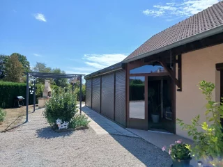 Véranda et terrasse avec volets roulants relevés à Bantanges